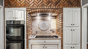 A kitchen with white cabinetry, a black oven, and a tiled backsplash. - Laurel Lane Oasis / Pool + Game Area + Near DFW (Bedford)