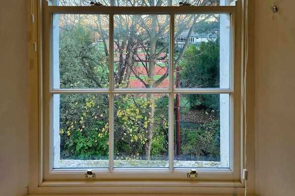 Ein Fenster mit Blick auf Bäume und ein Gebäude im Hintergrund.