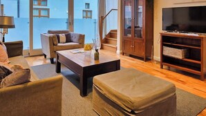 Un salon comprenant un canapé, un pouf, une table basse et un meuble pour la télévision.