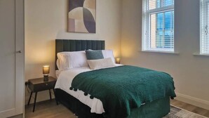 A bedroom with a bed, nightstands, a window, and a painting on the wall. - Stylish Base in Dublin’s Coolest Neighbourhood (Dublin 6)