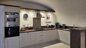 A modern kitchen with built-in appliances, a clock, and a coffee machine.