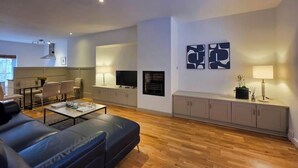 Ein modernes Wohnzimmer mit einer Couch, einem Couchtisch, einem Fernseher, einem Kamin und Kunstwerken an der Wand.