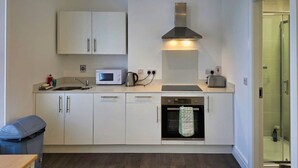 A modern kitchen with white cabinets, a microwave, a kettle, and a toaster. - Modern Open-Plan Apartment in Heart of Ranelagh (Dublin)