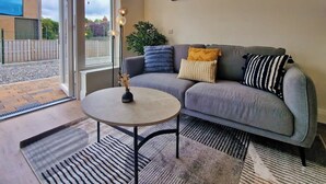 Un salon avec un canapé gris, une table basse ronde et une grande fenêtre.