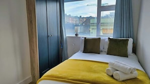 Et hotelværelse med en seng, et vindue med udsigt til bygninger og en dør.