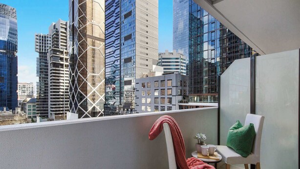 A balcony with a chair, a small table, and a potted plant. - Central 2BR Apt by Melbourne Central, City Views (Melbourne)