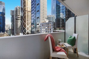 A balcony with a chair, a small table, and a potted plant. - Central 2BR Apt by Melbourne Central, City Views (Melbourne)