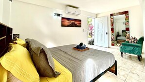 Un dormitorio con una cama, una silla, una puerta y un aire acondicionado instalado en la pared.