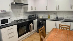 A modern kitchen with white cabinets, a microwave, stove, oven, and dishwasher. - OYO Dorset House At Upton Park (London)
