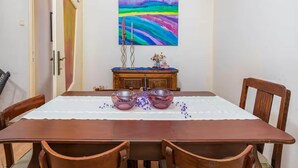 Un coin repas avec une table en bois, des chaises et un tableau accroché au mur.