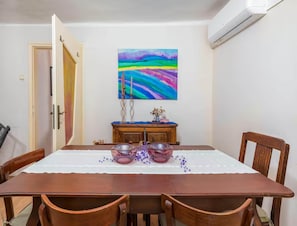 A dining area with a wooden table, chairs, and a painting on the wall. - Holiday Home With Perfect Interior (Vodnjan)