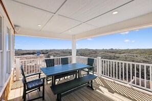 A covered outdoor deck with a table and chairs, white railings, and a view of the landscape. - Dennis -- Brand New in 2026! (Corolla)