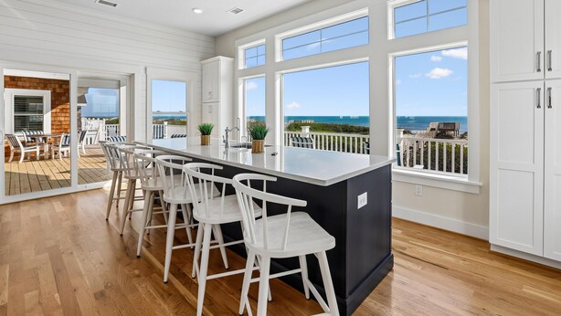 A kitchen with a large island, white bar stools, and a view of the ocean. - Fearing -- Brand New Oceanfront -- Ready for 2026! (Corolla)