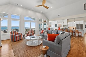 Ein geräumiges Wohnzimmer mit großem Fenster, Deckenventilator und Küchenbereich mit modernen Geräten.
