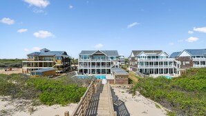 A beachfront property with multiple houses, a wooden boardwalk, and a swimming pool. - Fearing -- Brand New Oceanfront -- Ready for 2026! (Corolla)