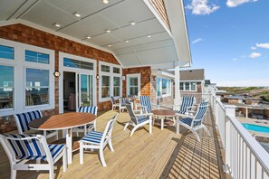 Eine überdachte Terrasse mit Sitzgelegenheiten und Blick auf den Pool.