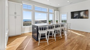 A kitchen with a large island, white bar stools, and a view of the ocean. - Fearing -- Brand New Oceanfront -- Ready for 2026! (Corolla)