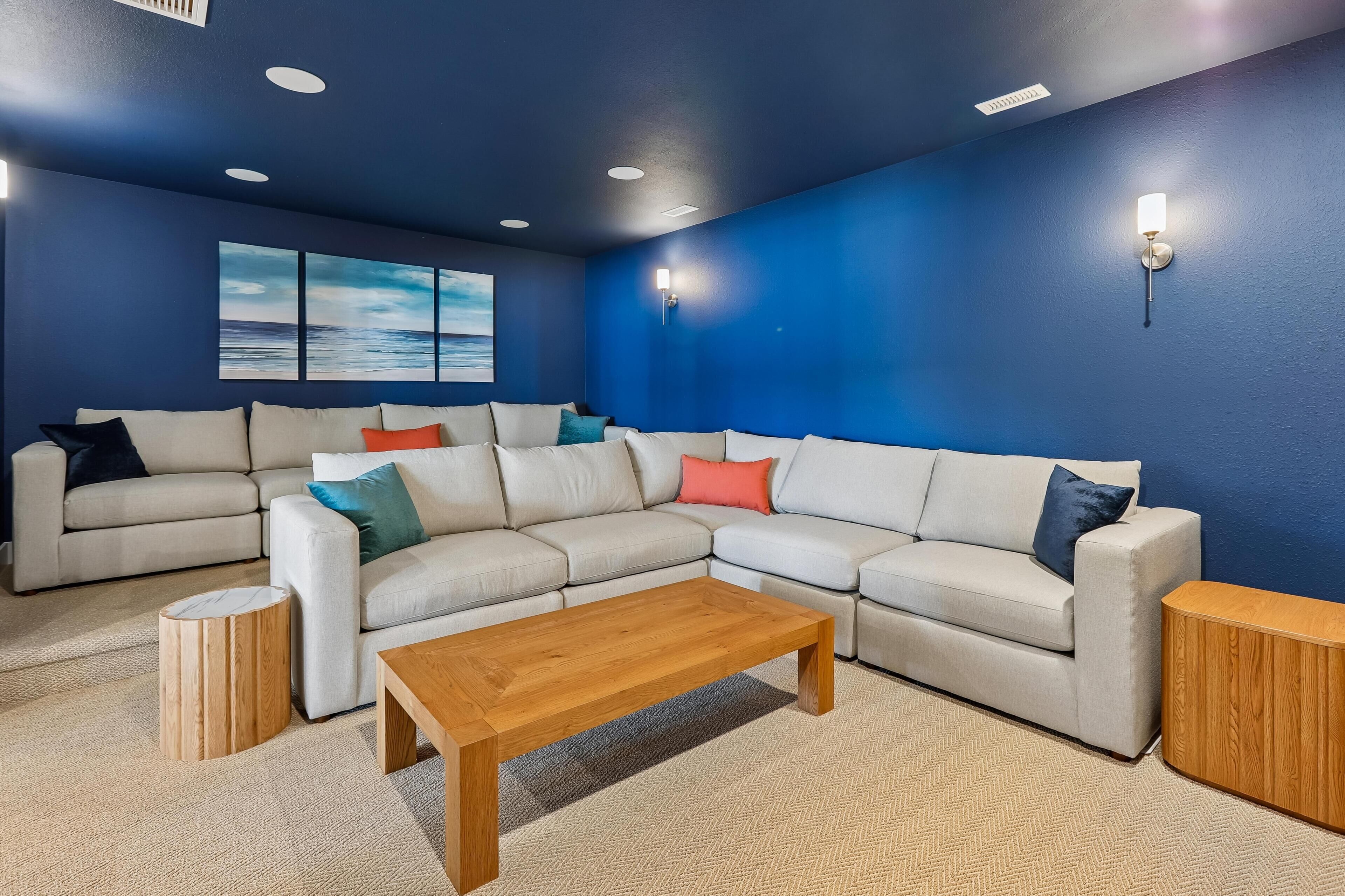 Un salon avec un canapé d’angle, une table basse en bois et un mur d’accent bleu.
