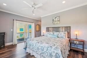 A bedroom with a bed, a ceiling fan, a nightstand, a lamp, and a view of a building outside. - Wild Horses -- Gorgeous Pet Friendly home in Corolla Bay (Corolla)