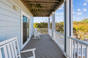A wooden deck with white railings and two rocking chairs. - Wild Horses -- Gorgeous Pet Friendly home in Corolla Bay (Corolla)