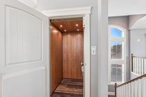 A hallway with a wooden elevator, a white door, and a window with blinds. - Wild Horses -- Gorgeous Pet Friendly home in Corolla Bay (Corolla)