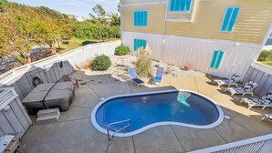 Un jardin avec une piscine, des chaises longues et un espace barbecue.