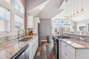 A modern kitchen with granite countertops, stainless steel appliances, and pendant lighting. - Wild Horses -- Gorgeous Pet Friendly home in Corolla Bay (Corolla)