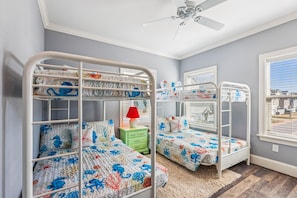 Ein Kinderzimmer mit Etagenbetten, einem Deckenventilator und einem Fenster mit Jalousien.