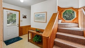 Un escalier avec des rampes en bois, une porte avec une fenêtre et un tableau accroché au mur.
