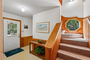 A staircase with wooden railings, a door with a window, and a wall-mounted picture. - New for 2026! Pet Friendly Duck Oceanside Home (Duck)