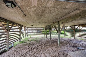 Ein Stall mit Sandboden, Holzbalken und Metallgeländern.