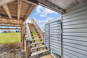 A wooden staircase leading to a metal door, with a clear sky in the background. - Herons Return -- Flexible Arrival and Stay Dates Year Round (Kitty Hawk)