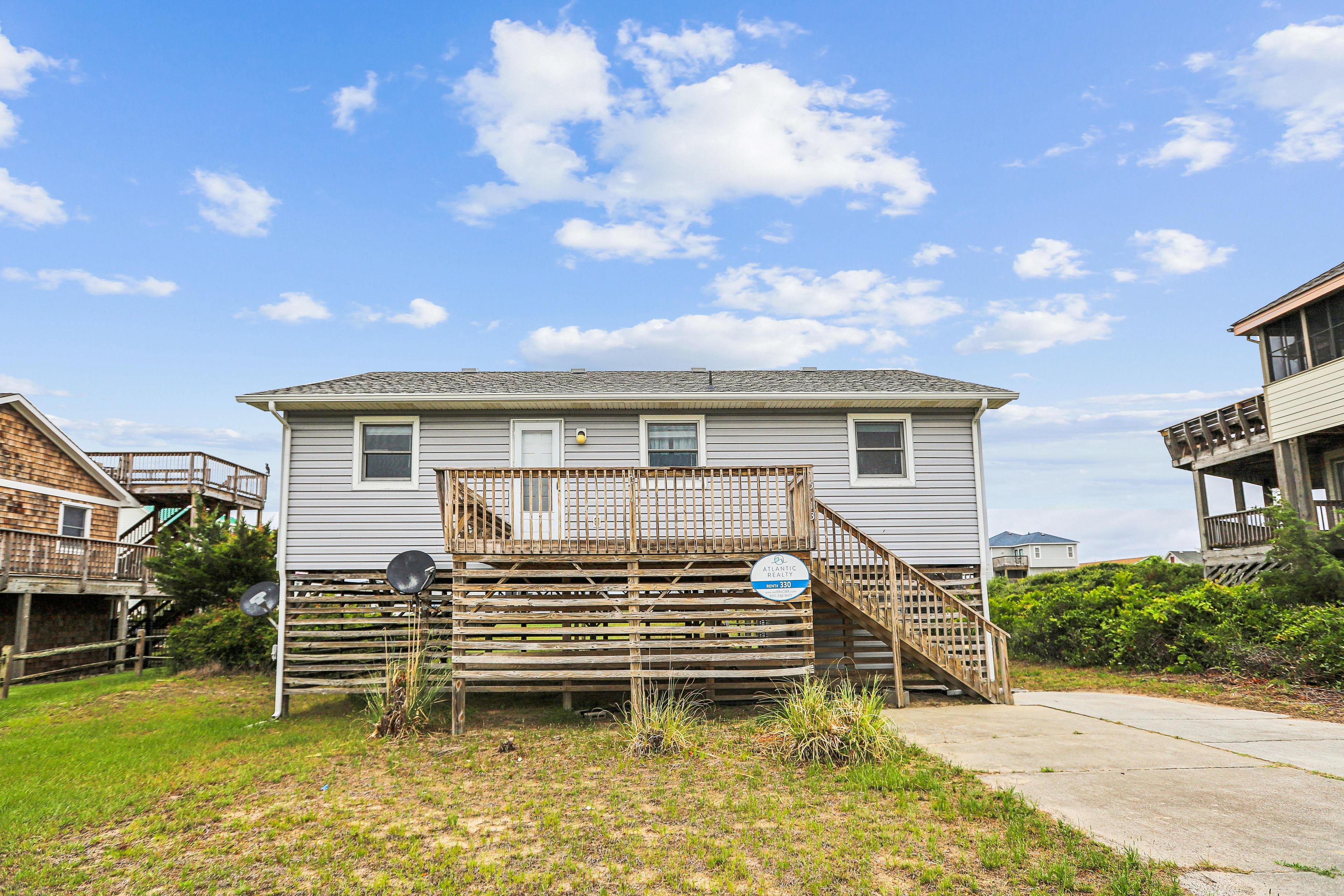A two-story house with a wooden deck and a satellite dish.