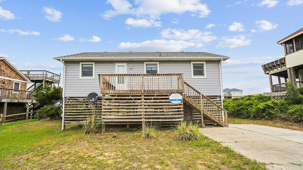 A two-story house with a wooden deck and a satellite dish. - Herons Return -- Flexible Arrival and Stay Dates Year Round (Kitty Hawk)