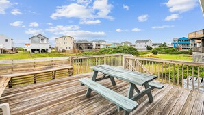A wooden deck with picnic tables overlooking a residential area with houses and a clear sky. - Herons Return -- Flexible Arrival and Stay Dates Year Round (Kitty Hawk)