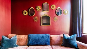 Una habitación con paredes rojas, un sofá y espejos decorativos.