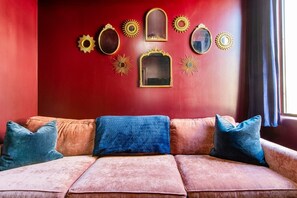 Ein Raum mit roten Wänden, einer Couch und dekorativen Spiegeln.