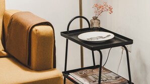 En hörna i ett rum med en golvlampa, ett litet bord med en vas och en soffa.