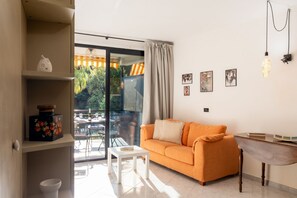 A modern living room with a sofa, a small table, and a view through a glass door to an outdoor area. - GuestHost - Bright 27 sqm studio apartment located on the second floor of a building with an elevator (NOT suitable for guests with disabilities).The accommodation is located in the Foce area, a very quiet and peaceful neighborhood and one of the most ch (Sanremo)