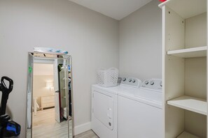 A laundry room with a washing machine, dryer, and a basket on top. - Bike to the Beach! Serene 1BR Sea Pines Condo / Pet Friendly! (Hilton Head Island)