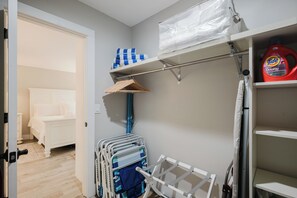 A bedroom with a neatly made bed, a closet with hanging space, and a shelf with a bottle of Tide laundry detergent. - Bike to the Beach! Serene 1BR Sea Pines Condo / Pet Friendly! (Hilton Head Island)