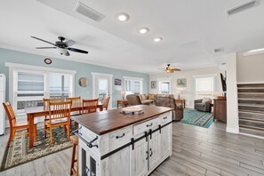 A spacious living area with a dining table, chairs, a sofa, and a kitchen island with cabinets. - Gulf Front | Community Pools | Beach Boardwalk (Gulf Shores)