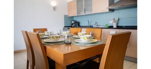 Een eettafel met witte borden en gele bekers, omringd door houten stoelen.