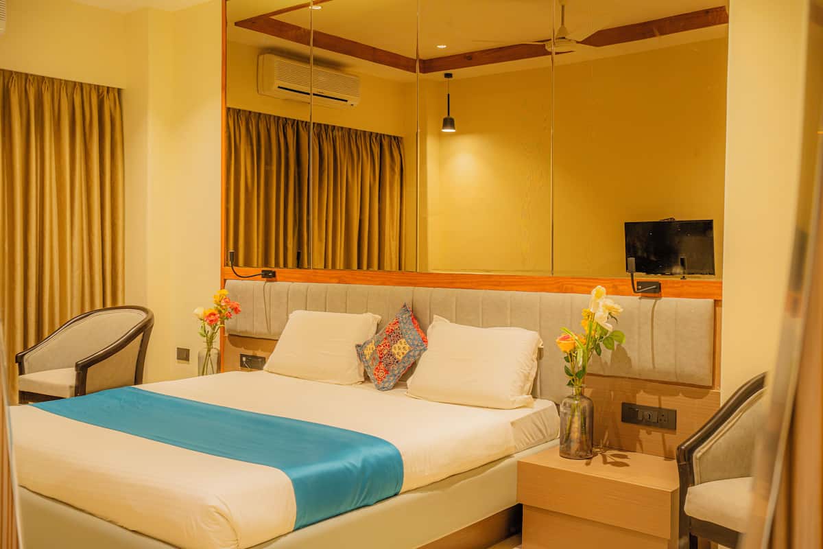 A hotel room with a bed, a nightstand, a chair, a TV, and a mirror.