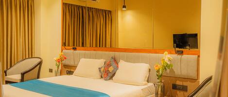 A hotel room with a bed, a nightstand, a chair, a TV, and a mirror.