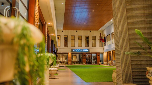A hotel corridor with a green lawn, a Food Land restaurant, and a modern ceiling design. - Hotel Prince Residency (Bhuj)