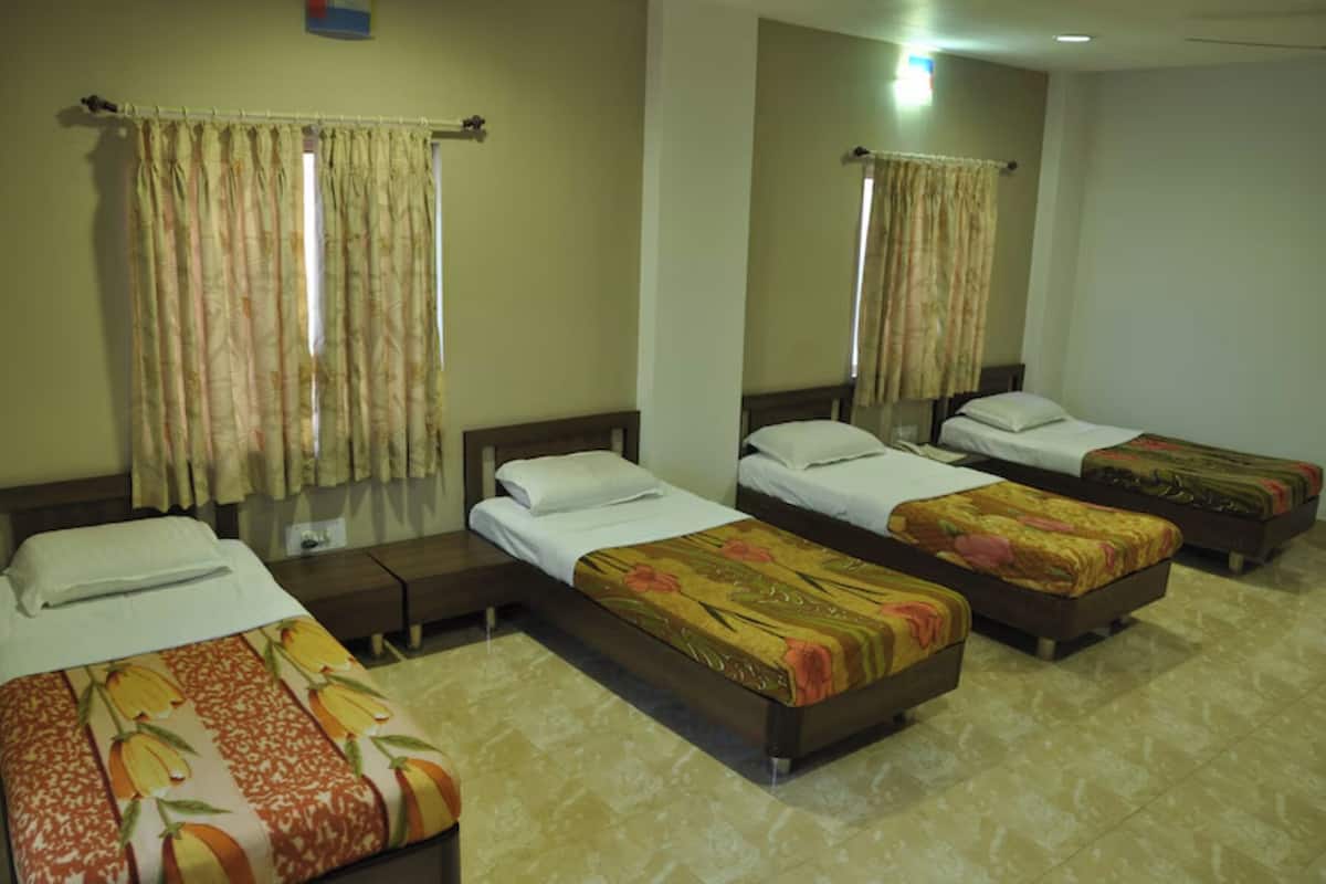 A hotel room with three single beds, a large mirror, and a window with curtains.