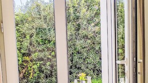 Uma porta de vidro dá acesso a um alpendre externo com mesa e cadeiras.