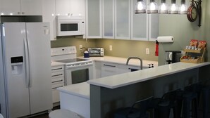 A modern kitchen with a refrigerator, microwave, stove, and sink. There are bar stools and a small island with a sink. - Smallwood St Park,Washington DC and Indian Head (Marbury)