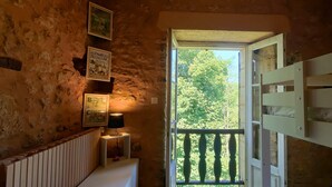A rustic room with a stone wall, a radiator, a small table with a lamp, and framed alphabet posters. - Exceptional gîte in the heart of a 12-hectare natural estate (Le Buisson-de-Cadouin)